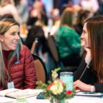 Two girls are talking at the table